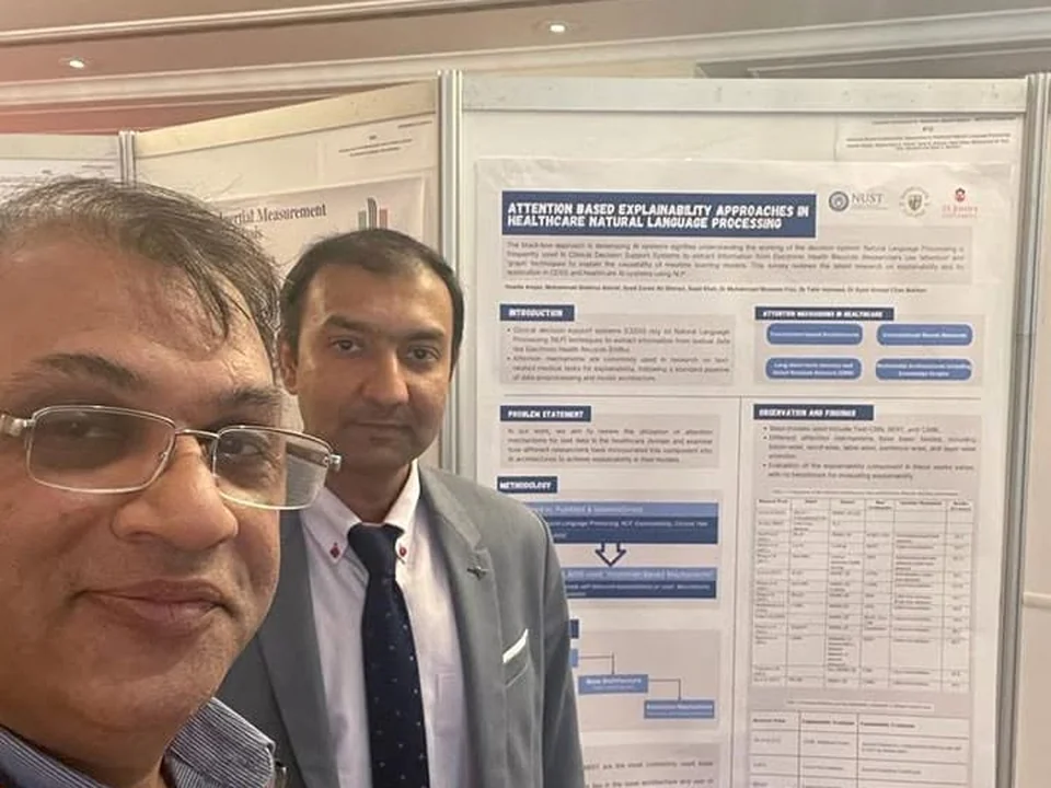 Dr. Bukhari and a colleague in front of a poster about attention-based explainability in healthcare natural language processing.